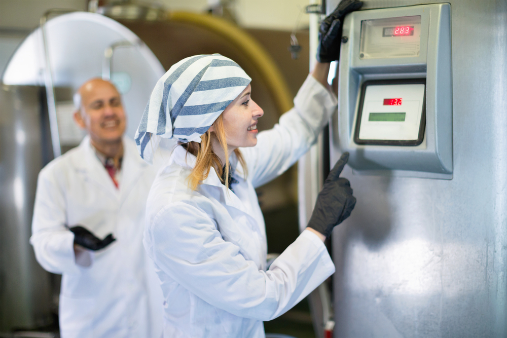 Smiling farm employees working in raw milk sector of livestock farm