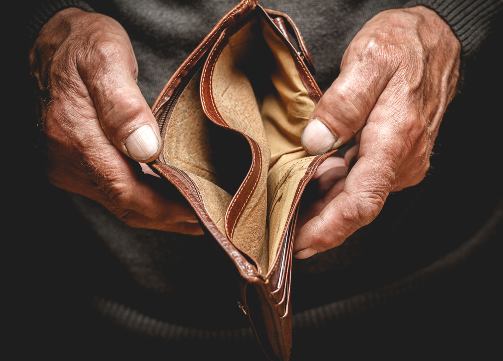 Empty wallet in the hands of an elderly man. Poverty in retirement concept