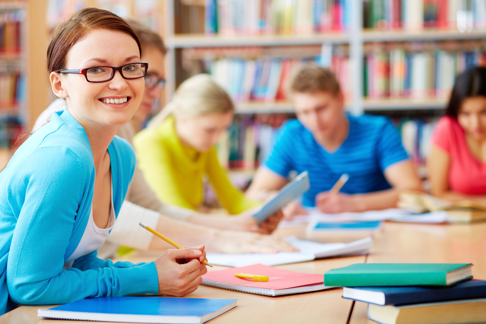 Portrait of pretty girl sitting in college library and looking at camera