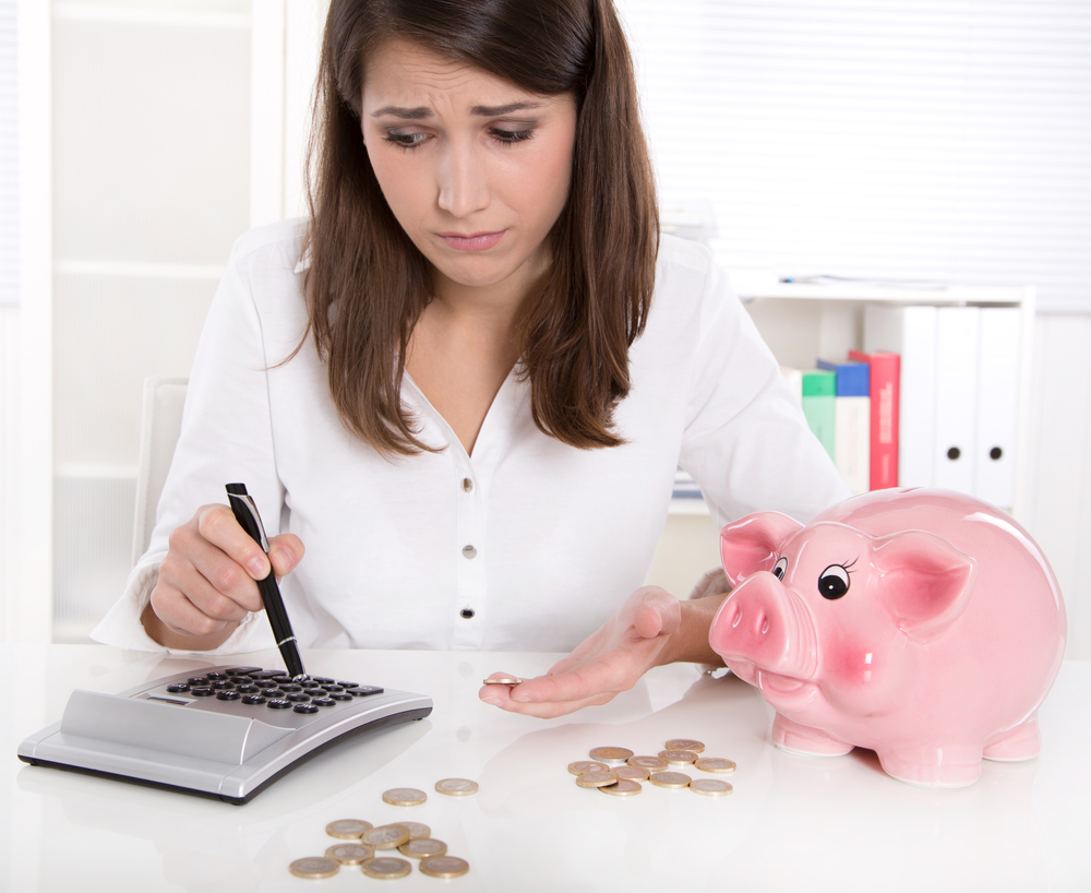 Woman is counting her money - sitting sad at desk and has lost her dreams