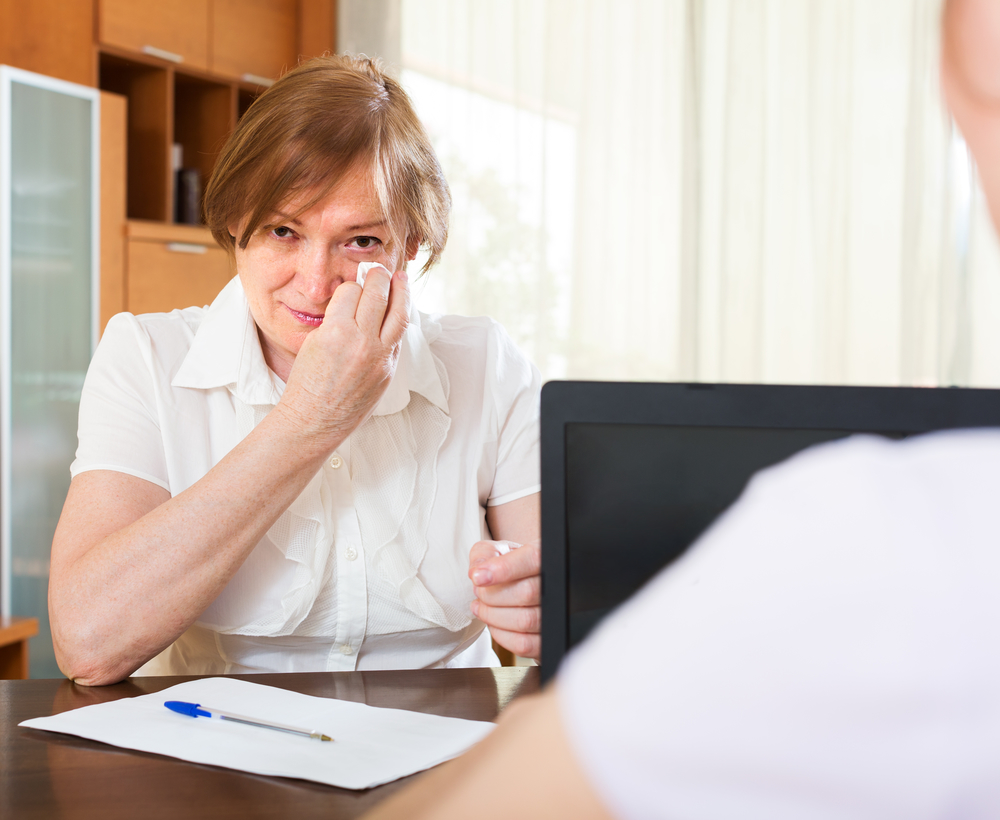 Mature woman answer questions of worker with laptop at table in home or office