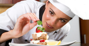 beautiful professional female chef decorating dessert