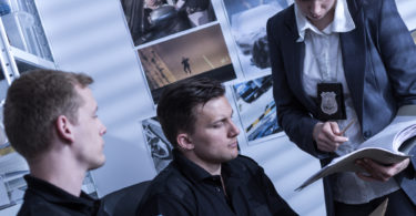 Two police officers and female detective working at a police station, analyzing evidences