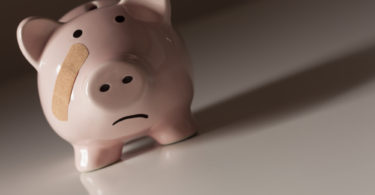 Piggy Bank with Bandage on Face on Dramatic Gradated Background.