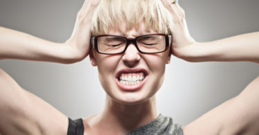 A beautiful young Caucasian woman in her twenties under stress pressure holding her head.