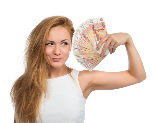 Happy young woman holding up many cash money five thousand russian rubles notes in hand looking at the camera isolated on a white background