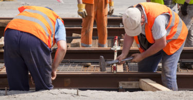 railway worker team in the street with a swinging a hammer