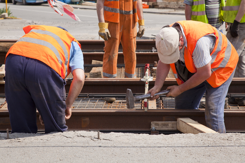 railway worker team in the street with a swinging a hammer