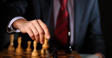 Image of a businessman in dark suit playing chess