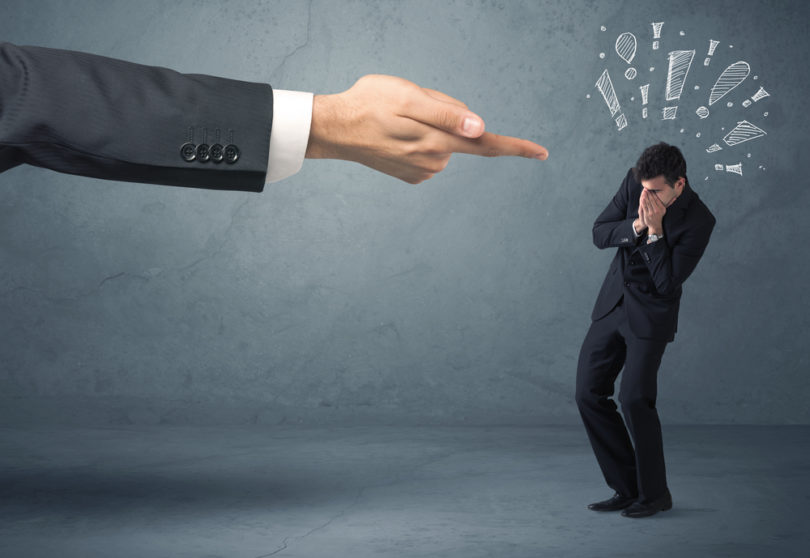 Employee in trouble getting last warning from boss concept with big business hand pointing at salesman and drawn exclamation marks