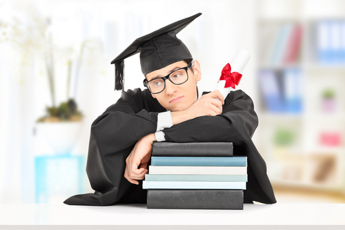 Worried college graduate leaning on a stack of books, indoors