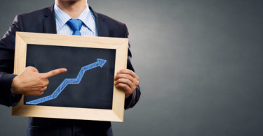 Unrecognizable businessman holding chalkboard with growth arrow concept