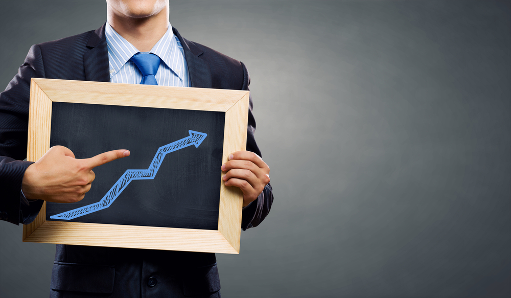 Unrecognizable businessman holding chalkboard with growth arrow concept