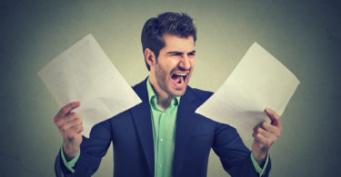 Angry stressed screaming business man with documents papers paperwork isolated on gray office wall background. Negative emotions face expression