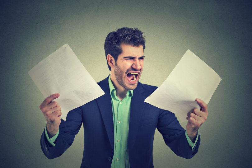 Angry stressed screaming business man with documents papers paperwork isolated on gray office wall background. Negative emotions face expression