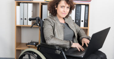 Disabled woman in wheelchair with a laptop working