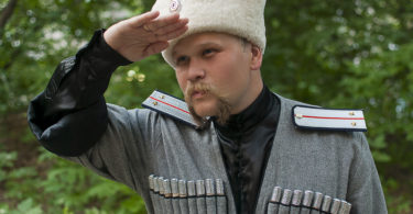 Young man in a cossack clothes in a forest