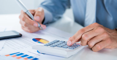 Close Up Of A Businessman With Documents At Desk Doing Calculations