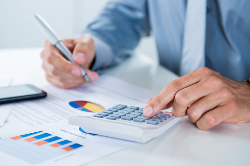 Close Up Of A Businessman With Documents At Desk Doing Calculations