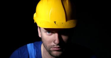 Portrait of young worker on dark background