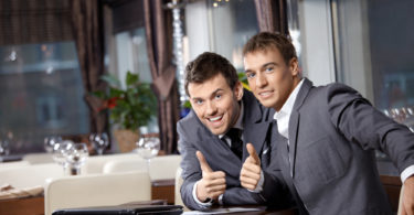 Two joyful businessmen at restaurant celebrate the transaction