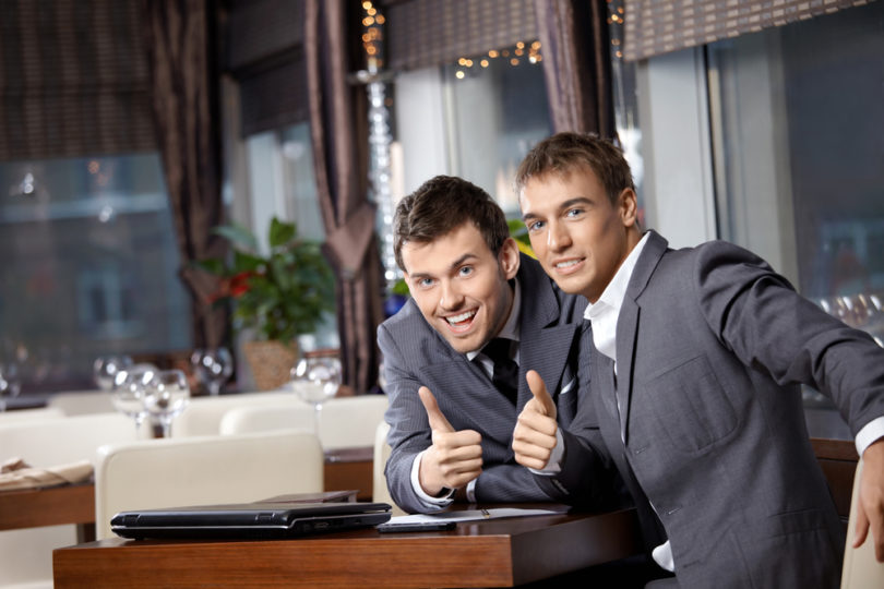 Two joyful businessmen at restaurant celebrate the transaction