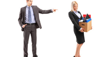 Full length portrait of an angry boss firing a woman with a box of her personal items isolated on white background