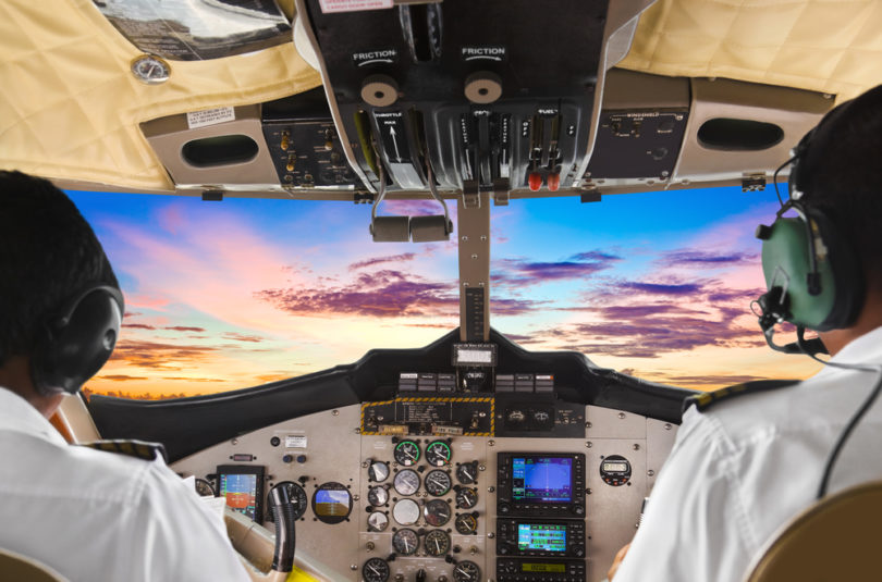 Two pilots in the plane cockpit and sunset