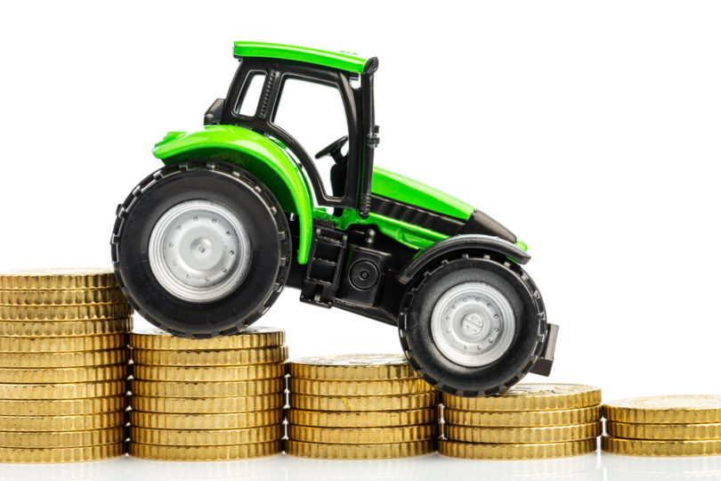 farmers in agriculture have to reckon with rising costs. higher preies in feed, fertilizer and plants. tractor with coins