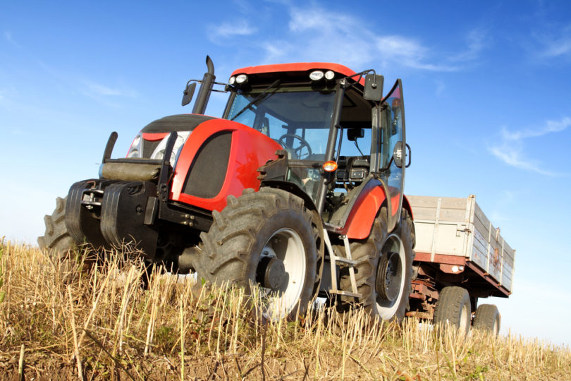 Agriculture - tractor on the field with harvested corn