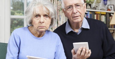 Senior Couple At Home With Bills Worried About Home Finances