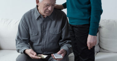 Poor senior man using calculator and counting money