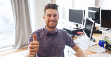 business, startup, gesture and people concept - happy businessman or creative male office worker with computers showing thumbs up