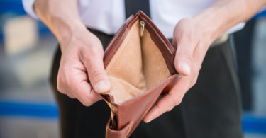 Close-up of man in suit holding empty purse.