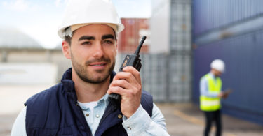 View of a Young Attractive docker using talkie walkie at work