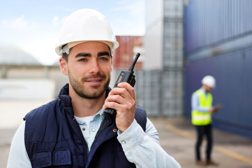 View of a Young Attractive docker using talkie walkie at work