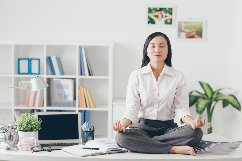 Female office worker meditating on her work place