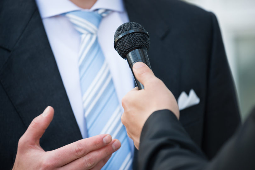 Midsection of male journalist taking interview of businessman outdoors