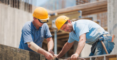 Authentic construction workers collaborating in the installation of cement formwork frames