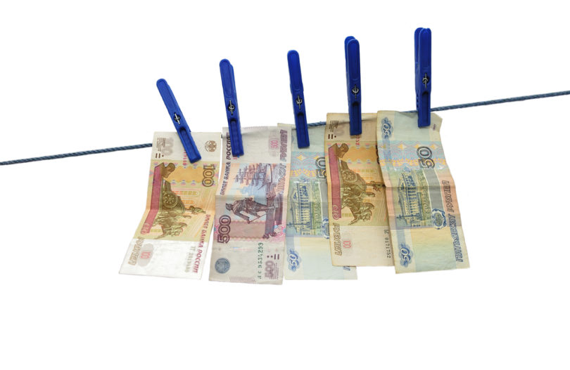 Russian rubles banknotes hanging on laundry line attached with plastic clothespins against white background