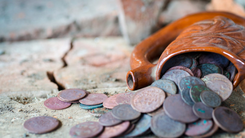 Ancient clay mug full of old coins. The treasure was found in an old building