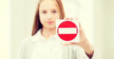 education, school and anti-bullying concept - student girl showing no entry sign