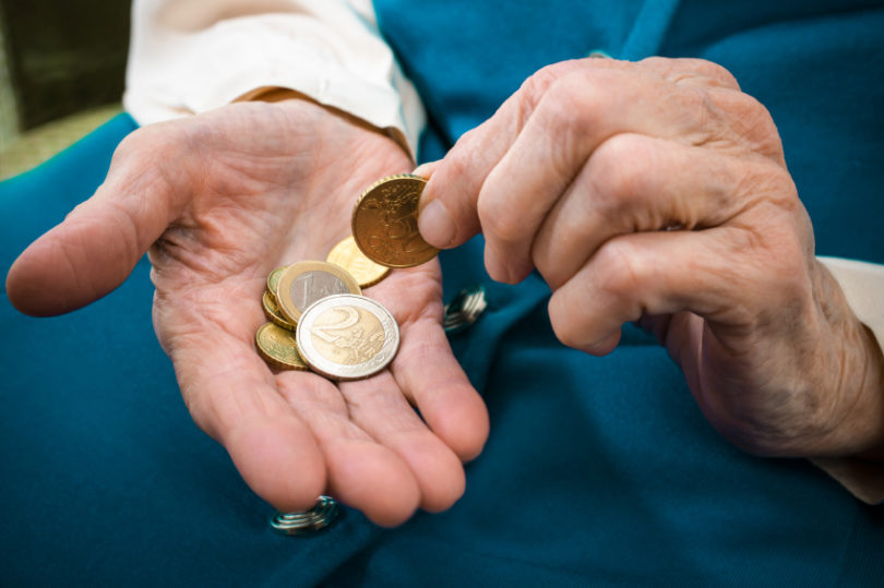 elderly caucasian woman counting money in her hands