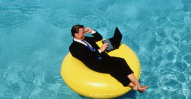 Businessman using laptop on float - Aruba