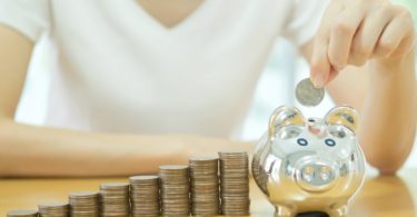 saving money-young woman putting a coin into a money-box-close up